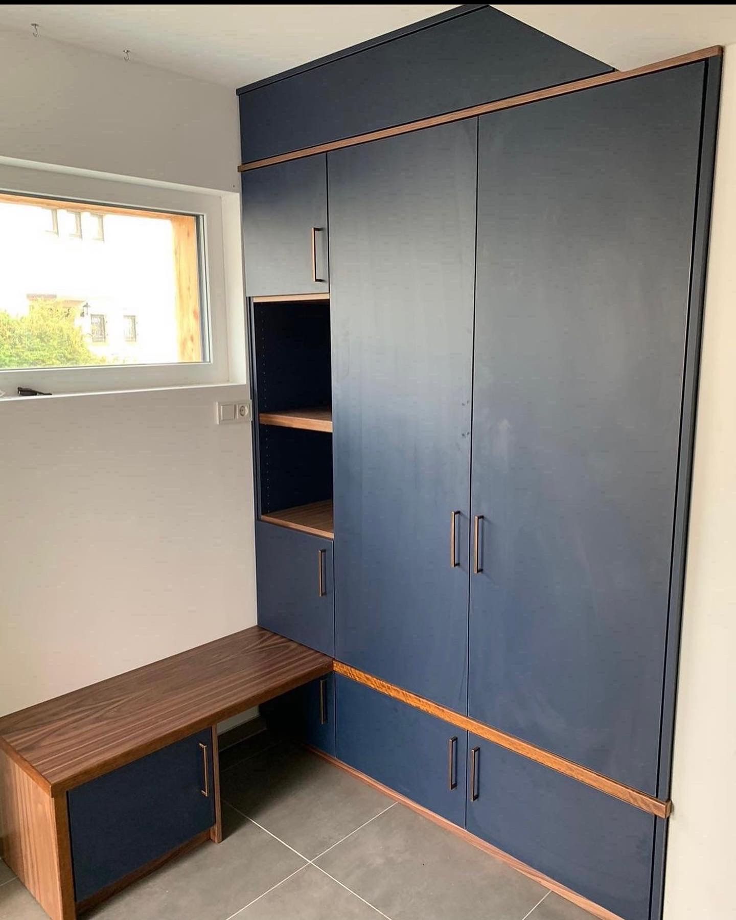 Raumhoher Einbauschrank in Blau mit Holzkanten und Sitzbank