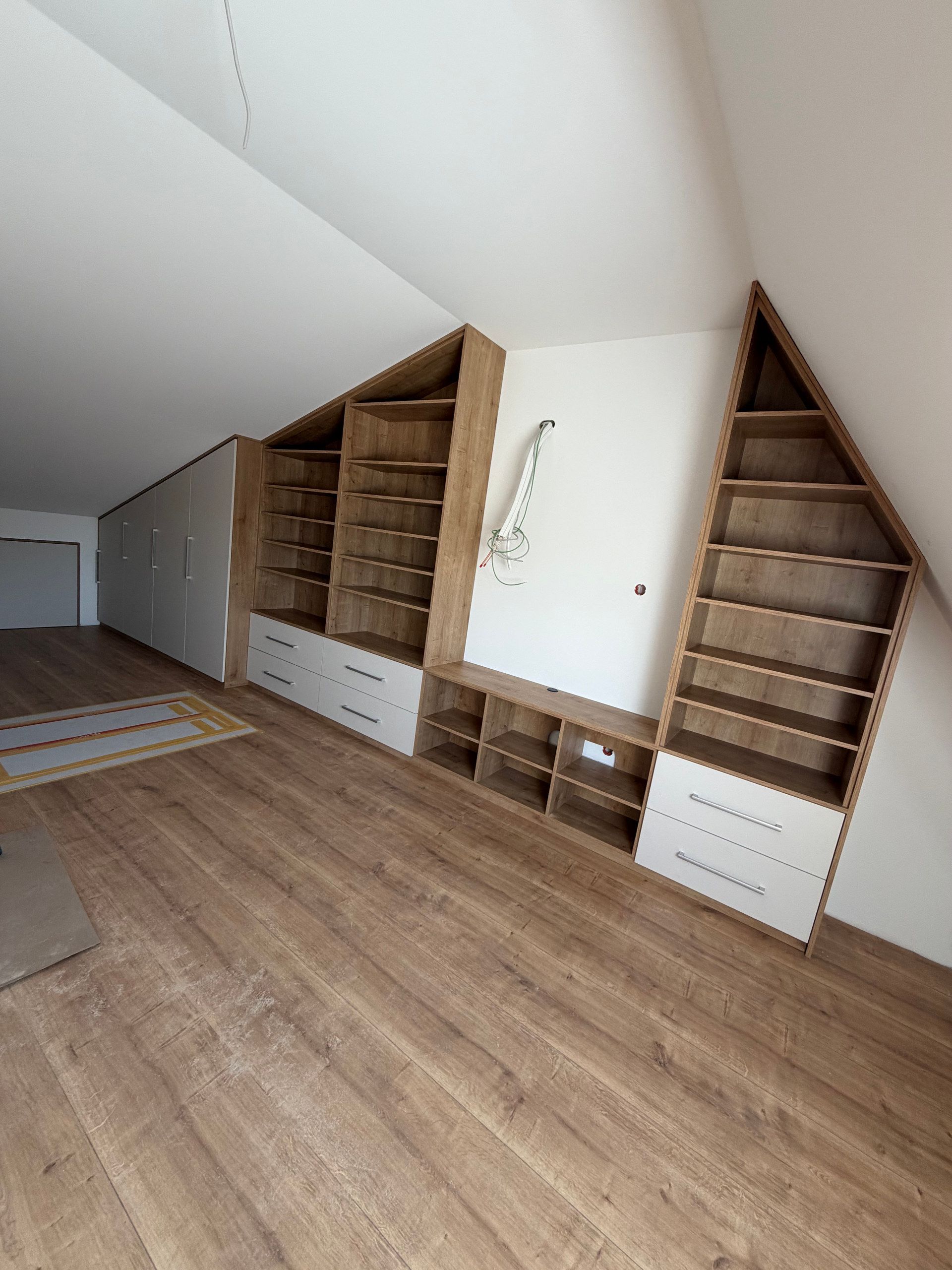 Dachgeschoss mit Regalwand in Holz und Schränken unter der Schräge