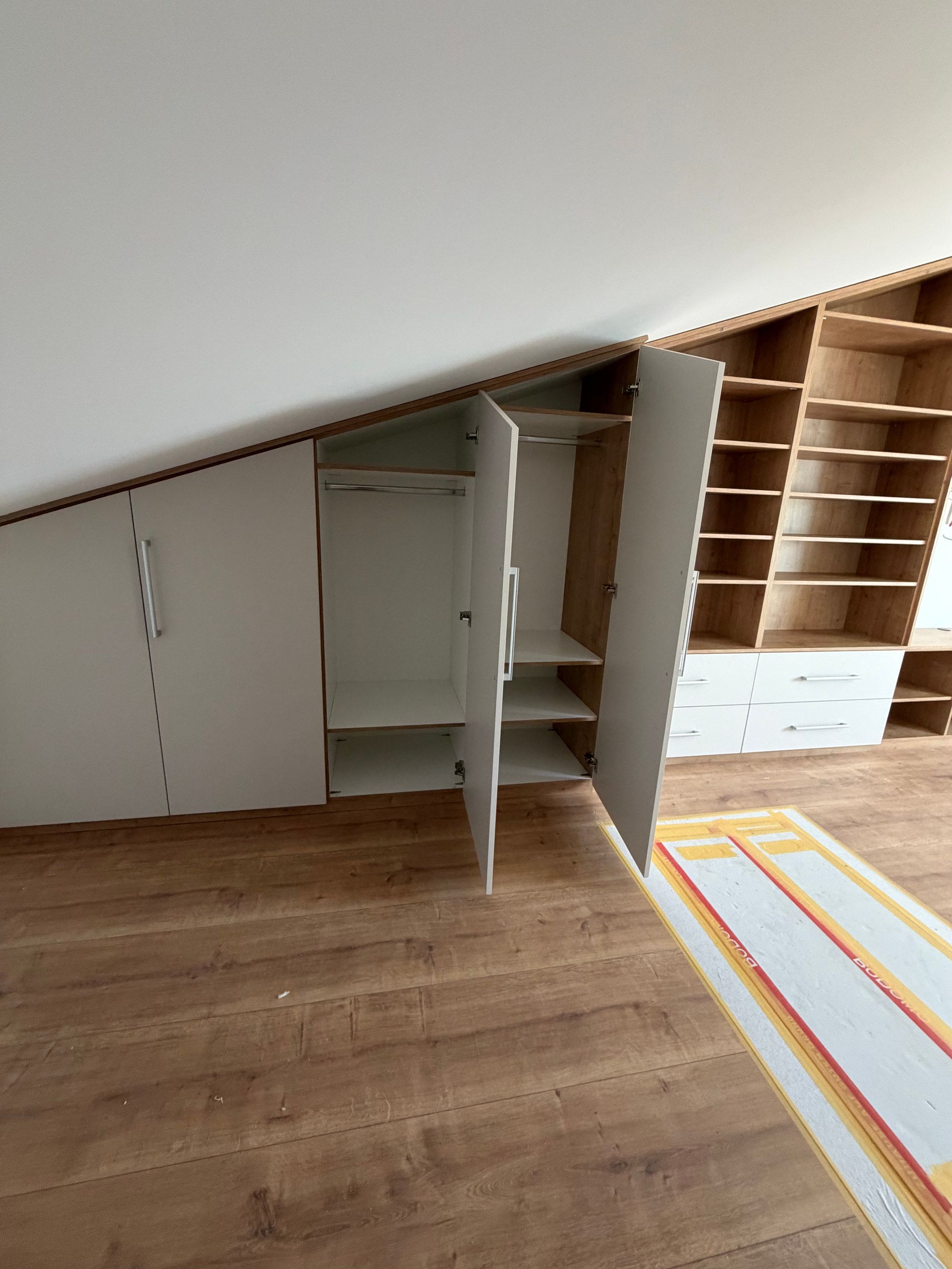 Geöffneter Schrank unter der Dachschräge mit Regalen