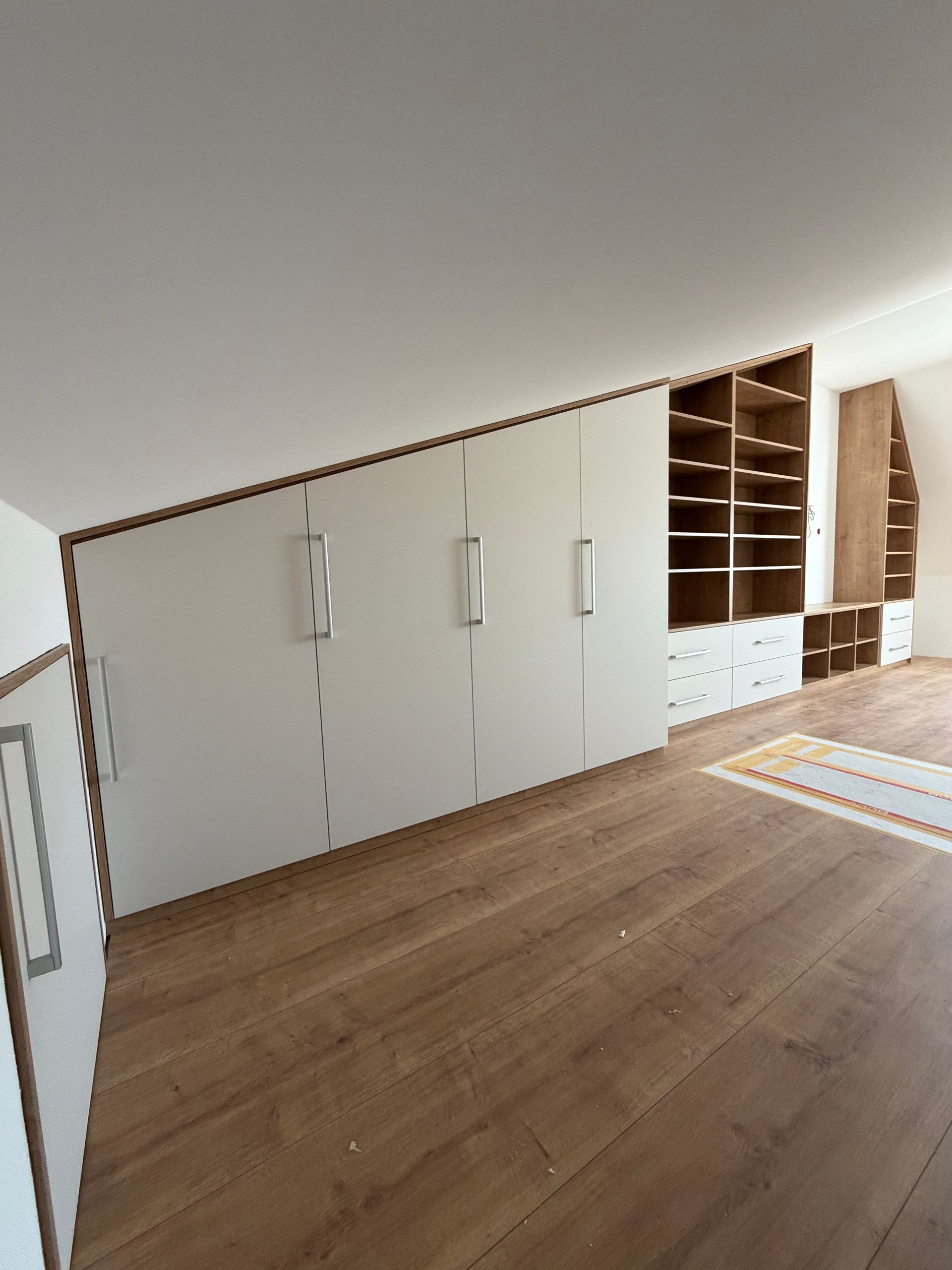 Weiße Schrankwand unter der Dachschräge mit Regalen