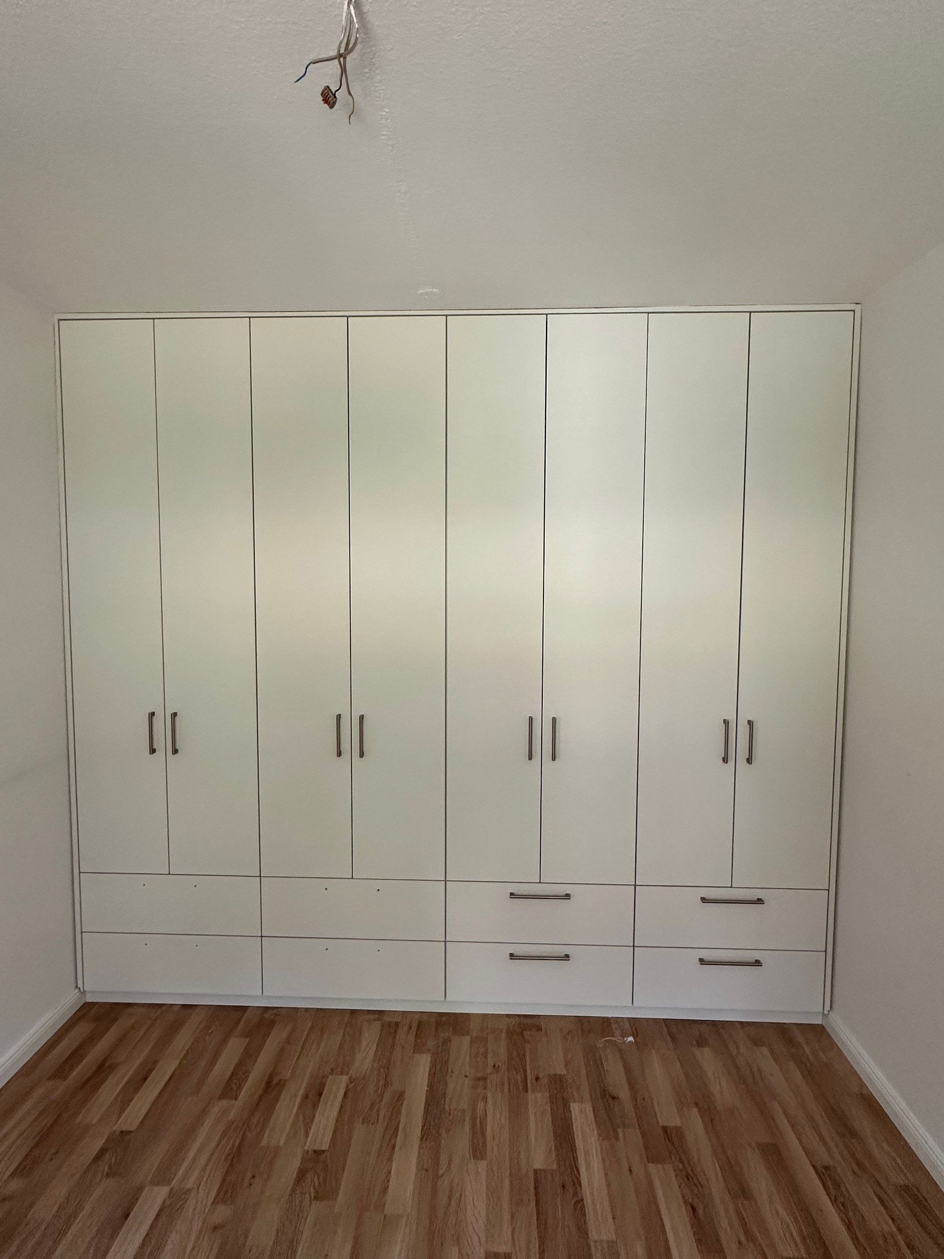 Weiße Schrankwand mit acht Türen und Schubladen