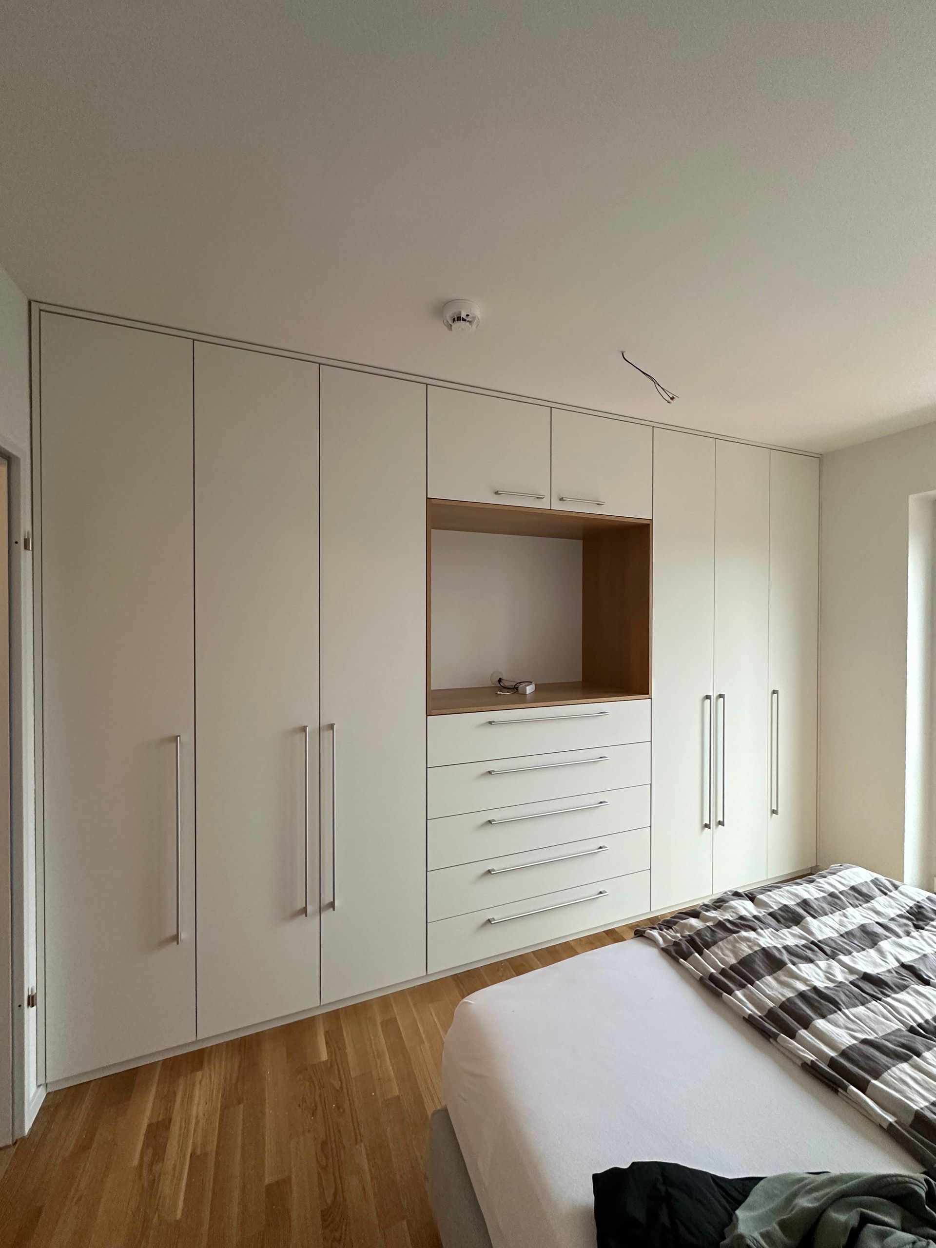Weiße Schrankwand mit Holznische und Schubladen im Schlafzimmer