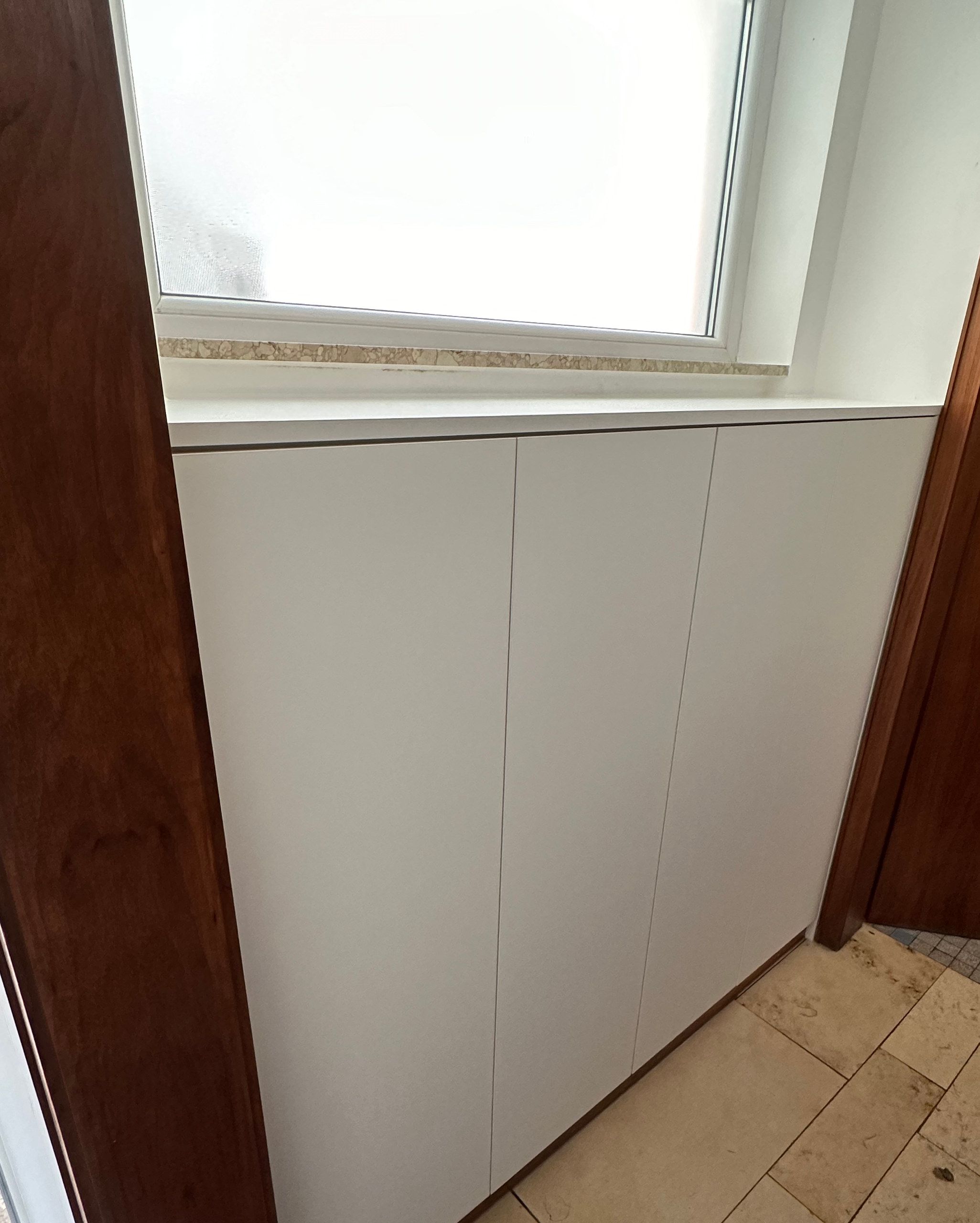 Weißer Einbauschrank unter dem Fenster