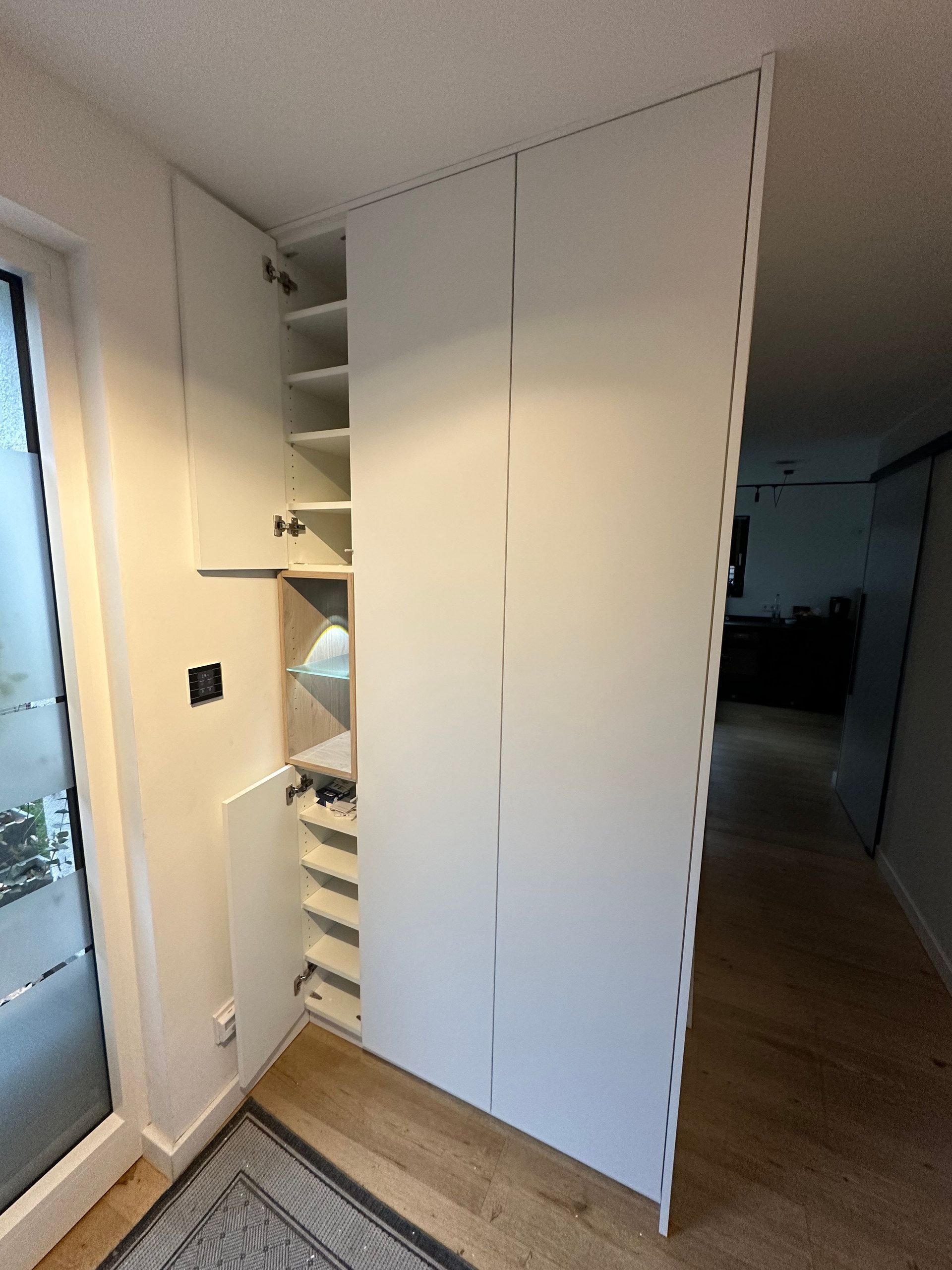 Griffloser weißer Einbauschrank im Flur, geöffnet