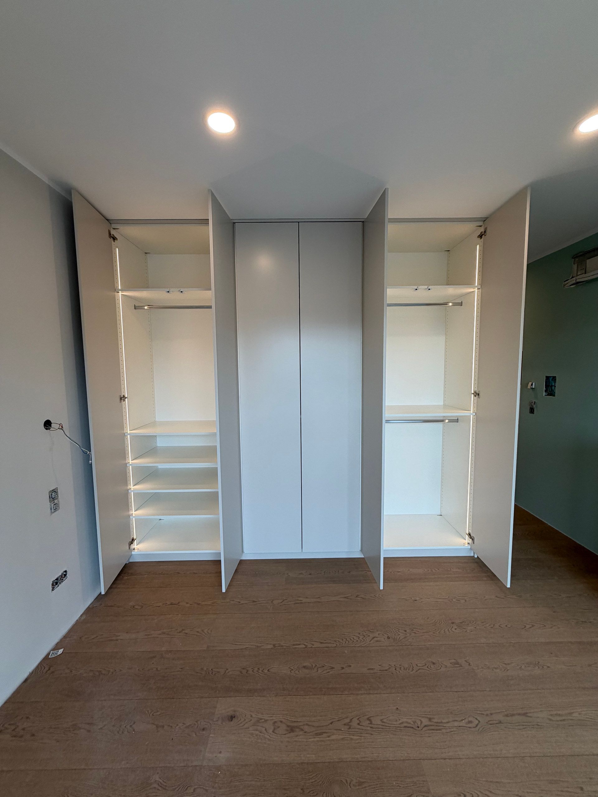 Raumhoher weißer Einbauschrank, geöffnet, mit Beleuchtung
