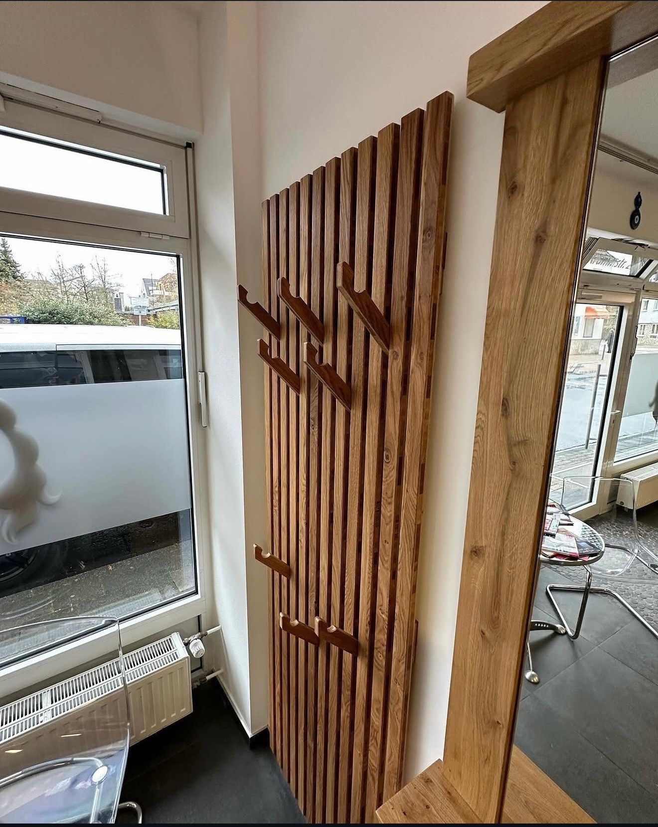 Garderobe aus Holzlamellen mit Haken in einem Ladenlokal