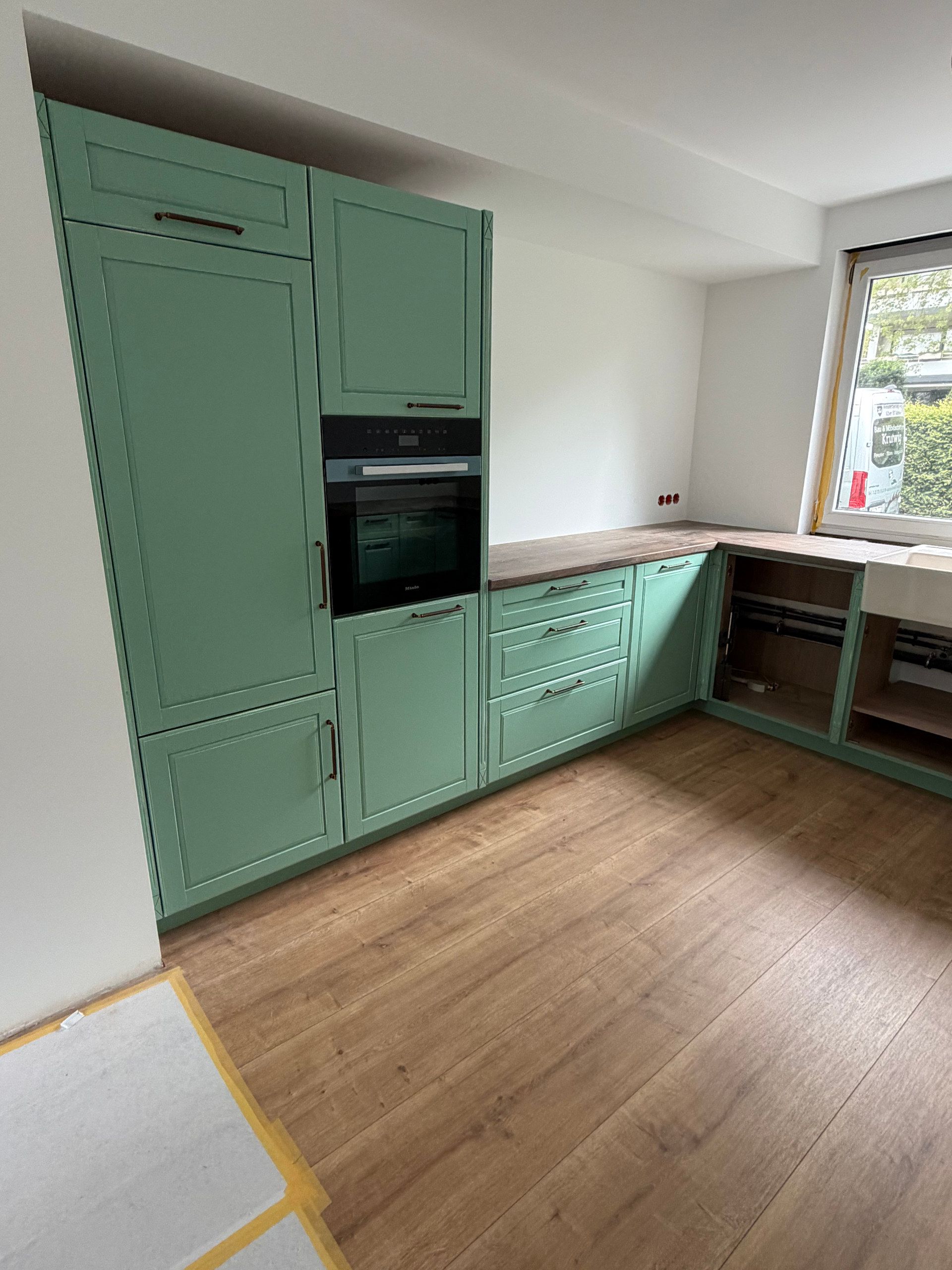 Grüne Landhausküche mit Hochschrank und Backofen