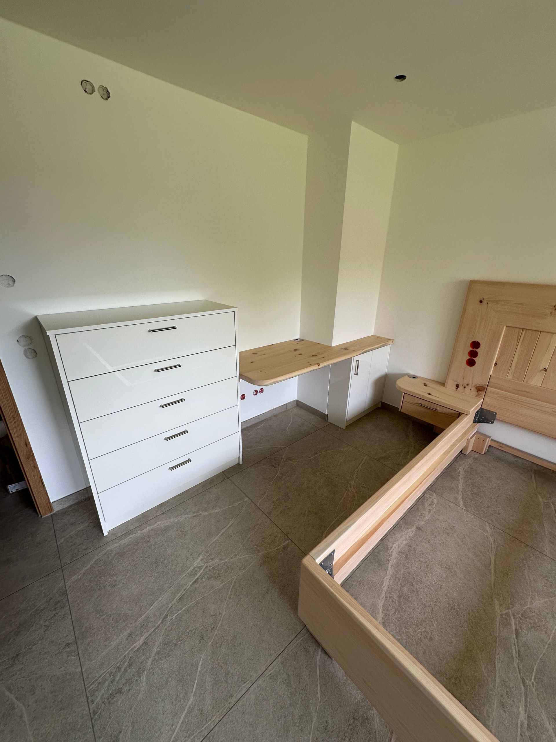 Zimmer mit weißer Kommode, Schreibtisch und Bettrahmen aus hellem Massivholz