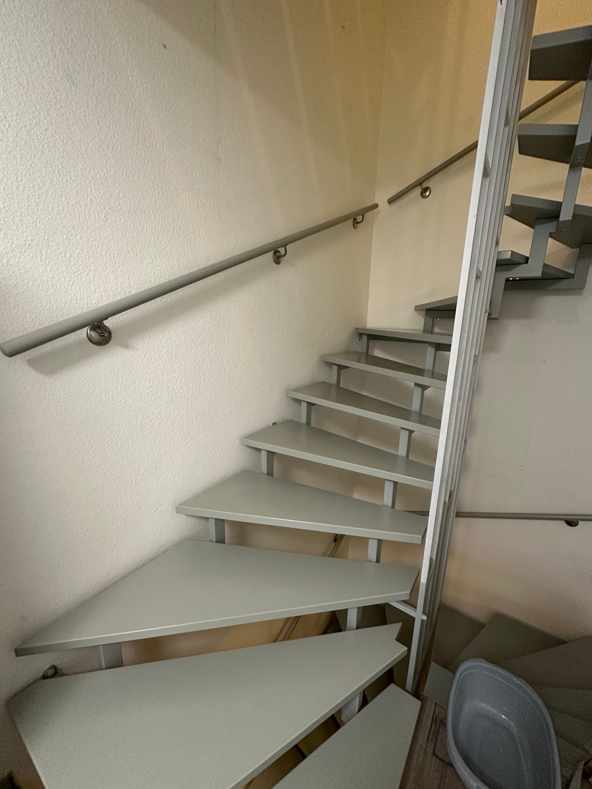 Graue Treppe mit Handlauf, von unten gesehen
